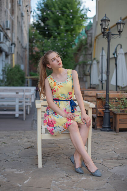 服饰一个穿着裙子的少女坐在街上的露台上快乐美女脸城市
