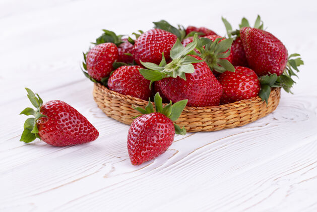 食物一个柳条碗里的多汁草莓 放在一张破旧的白色木桌上 乡村风格美味自然健康