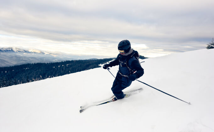 山滑雪者在白雪皑皑的山峰上倾斜转弯极限滑雪概念山景背景是灰色的天空行动斜坡高峰