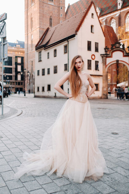 礼服在弗罗茨瓦夫老城 一个穿着婚纱留着长发的新娘女人华丽波兰