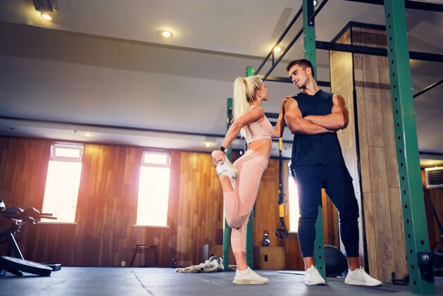 性感这对年轻夫妇正在健身房锻炼漂亮的女人和英俊的肌肉男在现代健身房里训练女孩形状运动