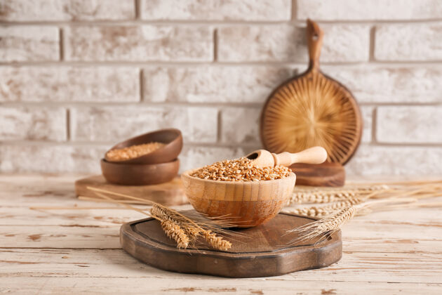 有机勺子和碗与小麦谷物在木制背景上膳食农业自然