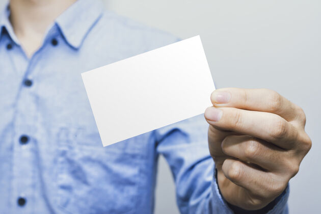 手拿着白色卡片纸的人 在白色样板上干净空白人