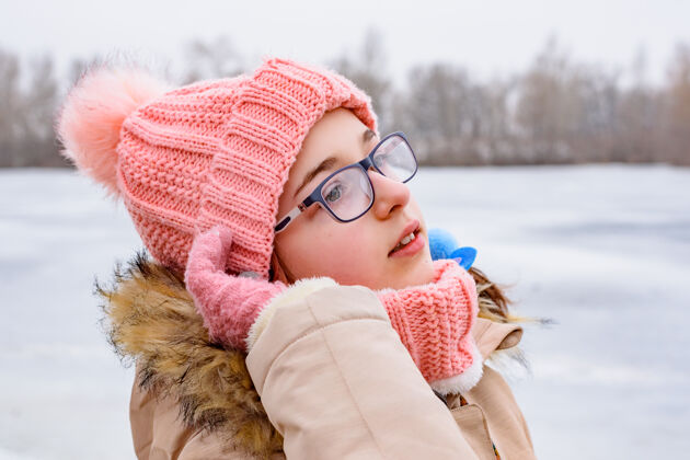 肖像戴着粉色帽子和外套的少女站在冬天的风景中一个可爱的孩子的冬天画像年轻女孩雪