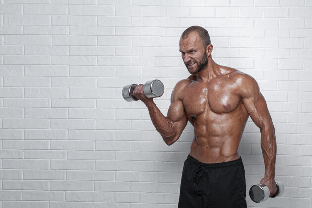 躯干健美运动员在砖墙上用哑铃练习二头肌肌肉质量男性