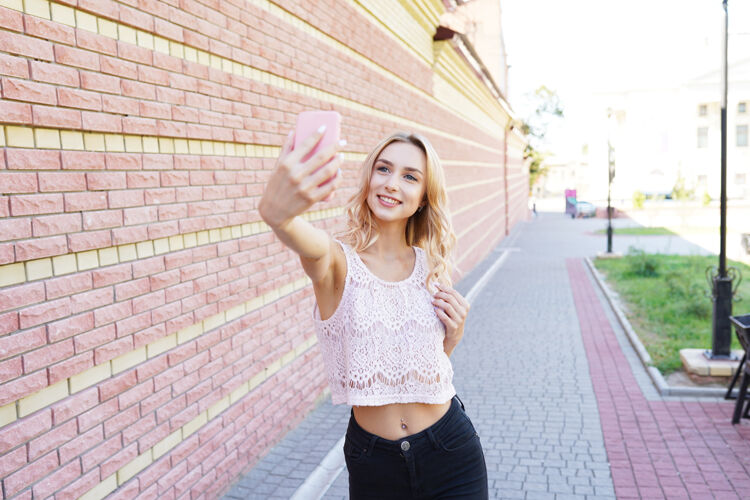 女孩年轻的金发时髦女人 自拍 在夏日的乡间摆姿势自拍户外休闲