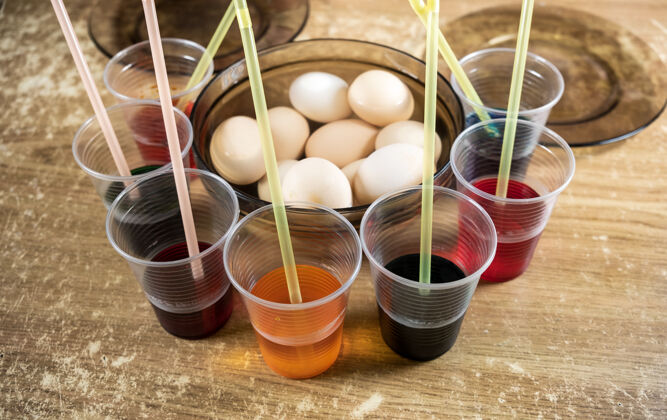 煮沸桌上的复活节彩蛋和彩色液体涂料 供孩子们在准备复活节的时候在白煮蛋上使用染料和涂料手持庆典五彩