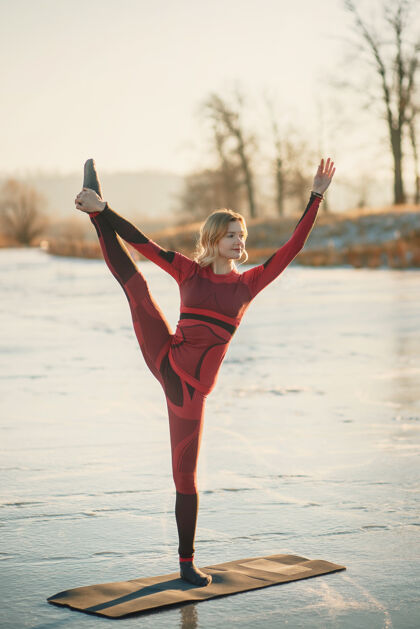 游泳冬天 一个女孩在日落时在湖边的冰上做瑜伽男人运动清晰