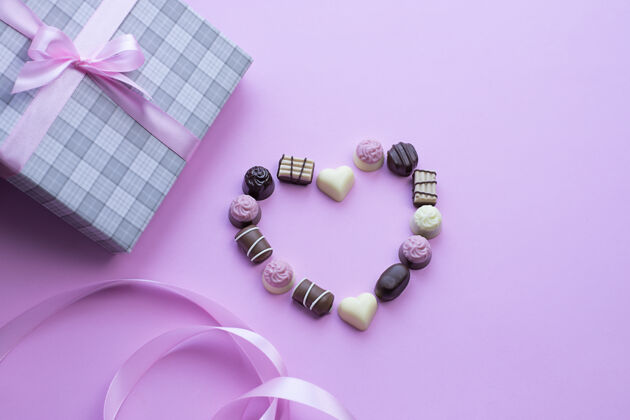 礼物心制成的巧克力pralines粉红色的背景图像与复制空间概念丝带节日