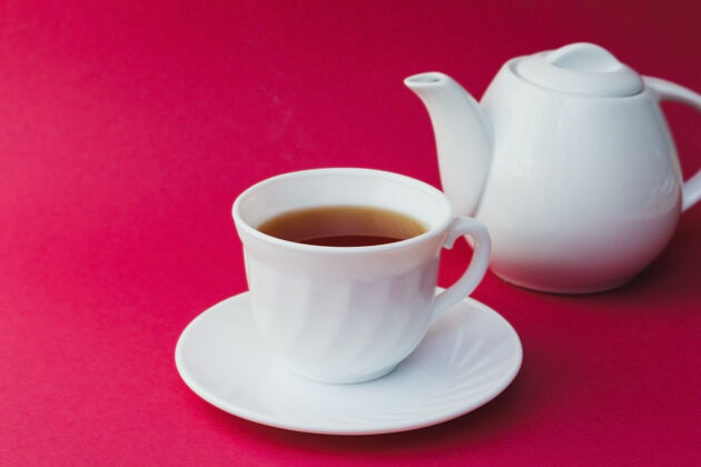 玫瑰粉红色桌子上的白杯茶草药茶壶厨房