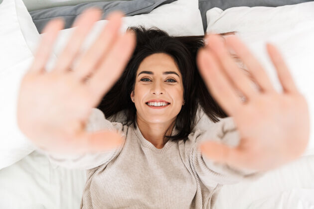 公寓图为30多岁的快乐女人躺在家里的床上微笑吸引力沙发室内