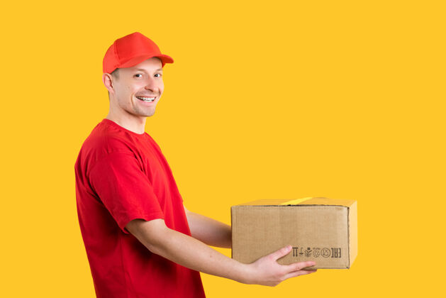 纸板穿着红色制服的快乐男信使拿着黄色的纸箱年轻信使人