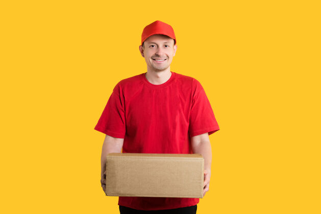 工人微笑的男信使身穿红色制服 手持纸箱或包裹 站在黄色的椅子上帽子肖像盒子
