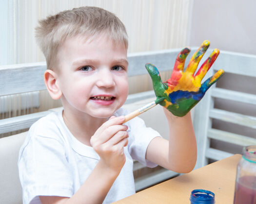 画男孩用不同的颜色装饰他的手绘画男孩画家
