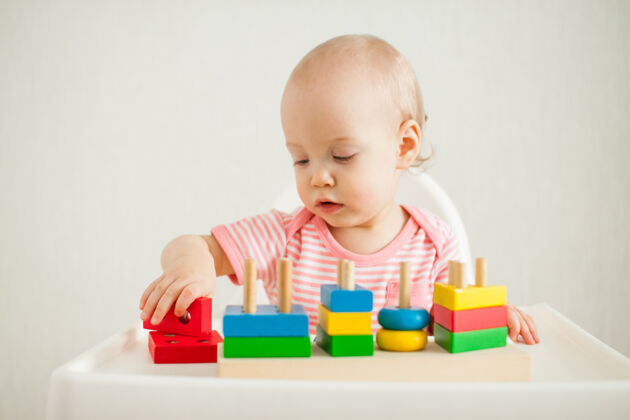 建设小女孩玩着一个教育玩具——一个五颜六色的木制玩具金字塔发展太好了操场游戏儿童发展