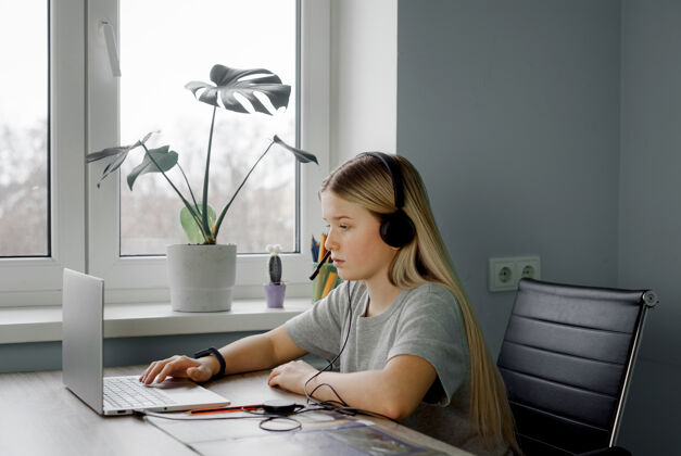 指导戴着耳机的少女在家里上网络课课程青少年女孩