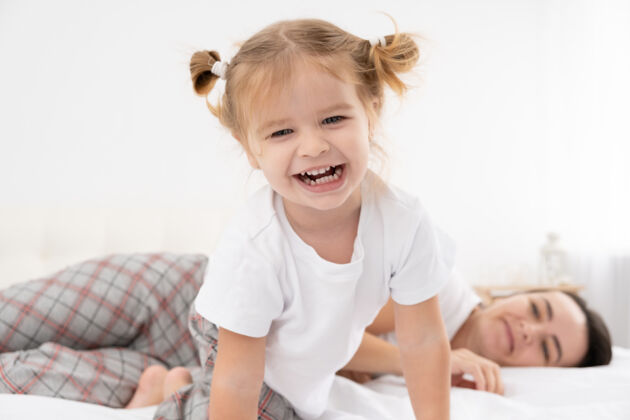 快乐的童年成年妈妈在家里和活泼的小女儿在床上玩耍 和孩子们一起玩 一起活动生活方式挠痒痒乐趣