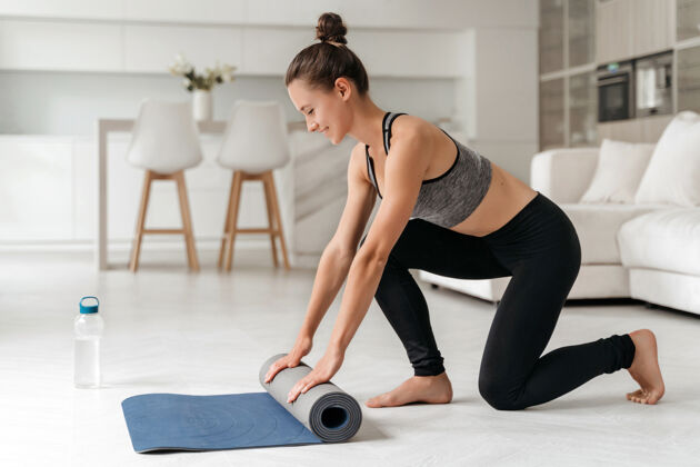 健康适合年轻女子展开瑜伽垫和准备健身锻炼或瑜伽课在家里身体会议房间