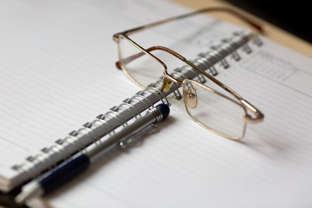 灵感把眼镜和笔放在打开的笔记本上 文件钢笔商业