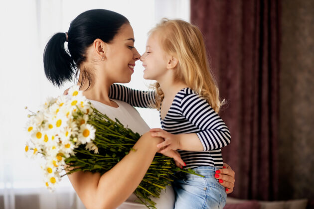爱爱心妈妈和小女儿在家拿着一束鲜花雏菊一家人在一起玩得很开心妈妈快乐庆祝