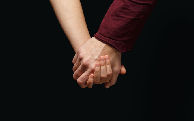 女性在黑暗的背景上 男人的手牵着女人的手救援关系手臂