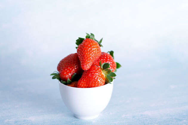食品美味的草莓放在蓝色背景的白色盘子里零食新鲜堆栈