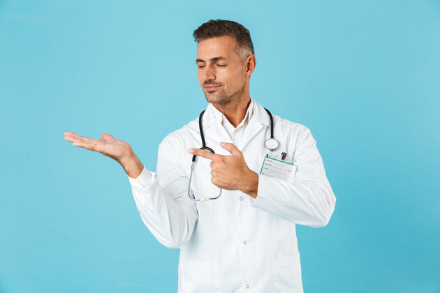 东西带听诊器的成年医生的画像 孤立地站在蓝色的墙上专业知识职业工人