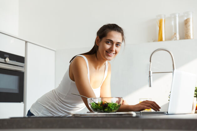 室内健康的女人每天早上都站在厨房沙拉旁边马克杯快乐休闲
