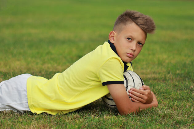 足球帅哥足球运动员带着球躺在足球场上运动员竞争欢乐
