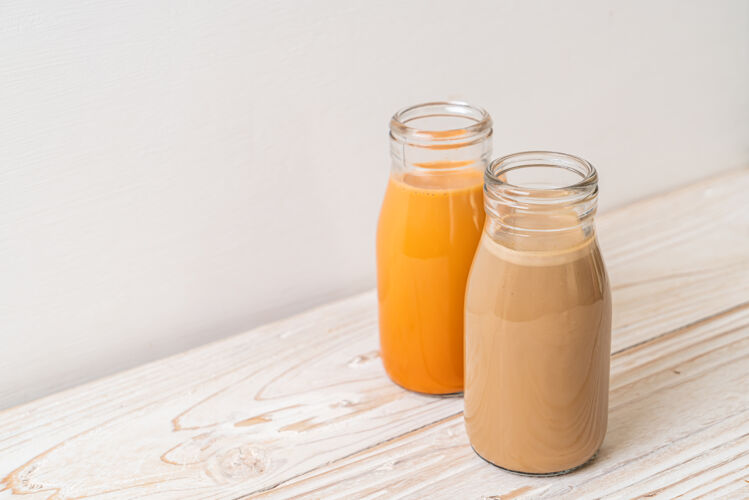 提神泰式奶茶和牛奶咖啡放在木桌上的瓶子里浓缩咖啡糖棕色