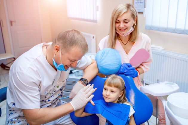 女人牙医和可爱的孩子在牙科诊所治疗牙齿后 微笑着打招呼护理检查仪器