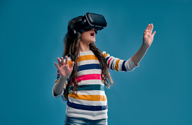 女孩孩子们在蓝色上体验虚拟现实设备互动游戏