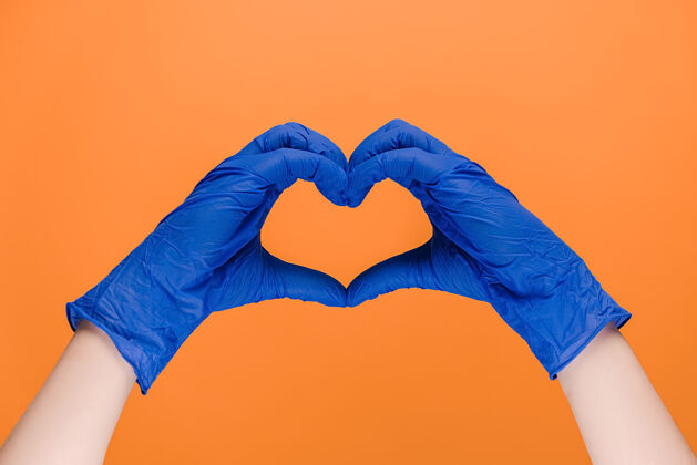 墙壁男性手戴医用手套做心脏符号快乐展示护士
