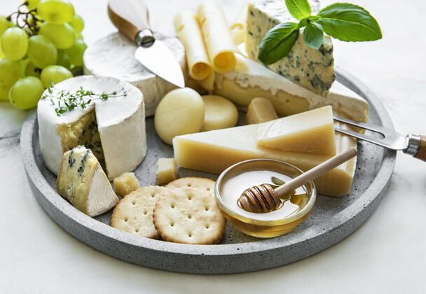一块奶酪大理石桌上摆着各种各样的奶酪 葡萄和蜂蜜产品套装食品