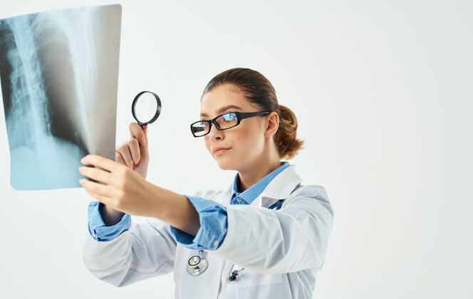 护士女医生手里拿着放大镜和胸部x光片医师年轻办公室