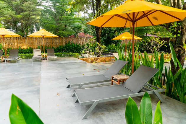 天堂酒店度假村游泳池周围的雨伞和泳池床装饰椰子放松休息室