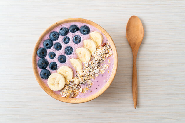 排毒酸奶或酸奶冰沙碗配蓝莓 香蕉和牛奶健康麦片美食风格紫色混合浆果