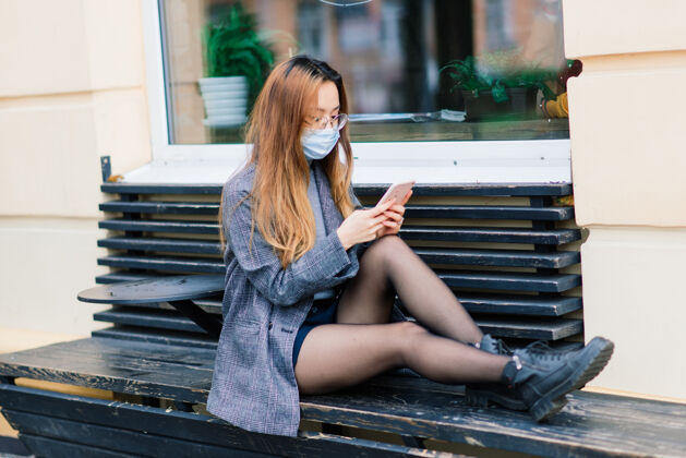 环境带着口罩的亚洲女人 城市里的护面 咖啡馆避免咳嗽城市