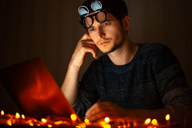 黑暗戴着墨镜的年轻人的画像 在黑暗的房间里用笔记本电脑工作眼镜企业家商务人士