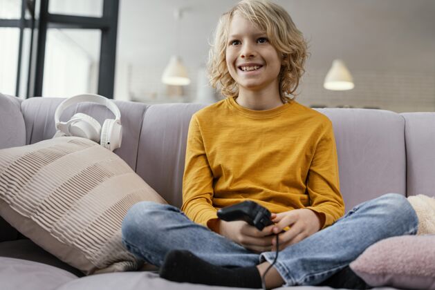 科技坐在沙发上玩游戏的男孩男孩设备室内
