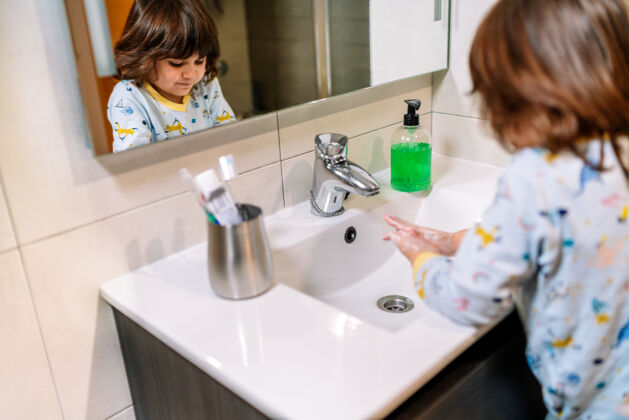 消毒反映幼儿在用肥皂洗手的同时穿着睡衣在预防和保护冠状病毒19型日常年轻卫生
