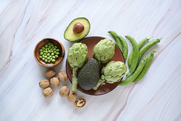 饮食洋蓟 鳄梨 核桃和绿豆以大理石为背景 健康健康的生活理念健活平衡豆荚