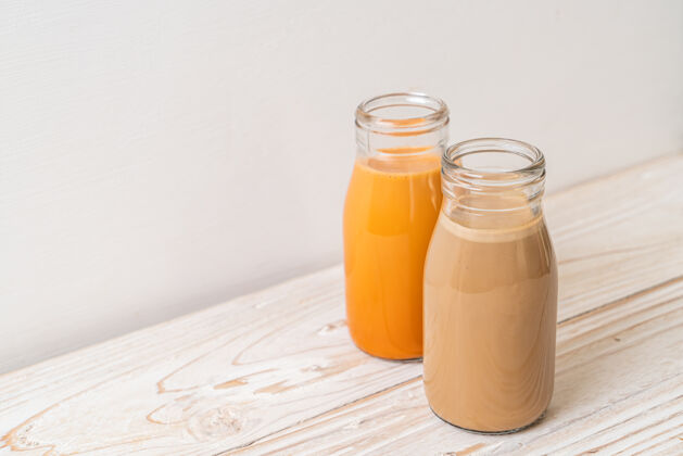 提神泰式奶茶和牛奶咖啡放在木桌上的瓶子里浓缩咖啡糖棕色