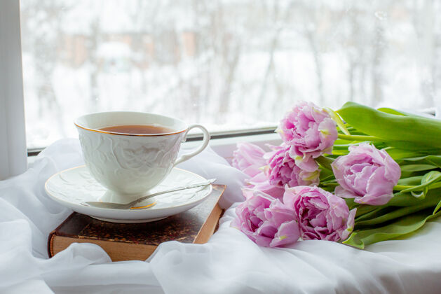 木板一杯茶一本旧书一束郁金香在窗户上健康杯子郁金香花束