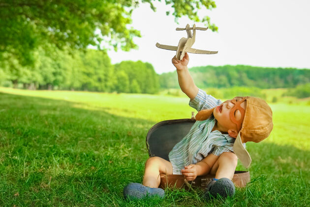 玩具飞机旁的一个男婴在空中玩弄大自然公园男孩度假飞行员生活方式葡萄酒假期
