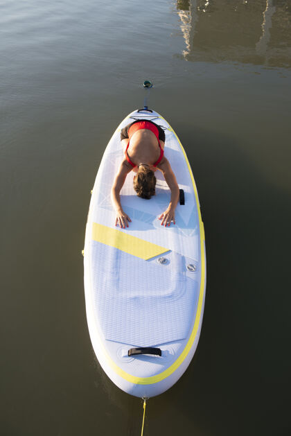日落日出时准备在划桨板上练习瑜伽的女人和谐健康日出