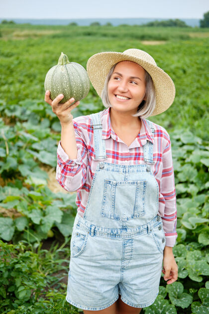 健康一个女人手里拿着绿色的新鲜南瓜在田里植物田野温暖