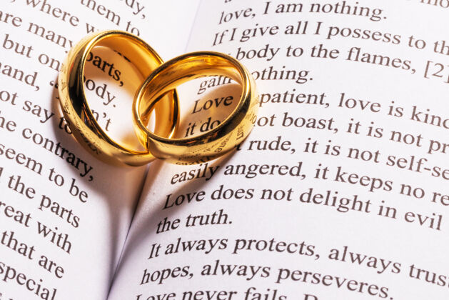 订婚两个金色的结婚戒指在圣经书特写在一起永恒团结