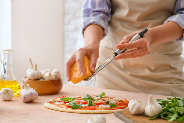 奶酪一个女人在厨房里磨比萨饼上的奶酪碗桌子板