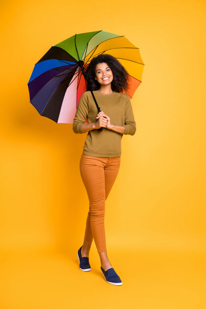 雨垂直全长体型照片欢快可爱的卷曲波浪迷人的积极的女朋友穿着裤子裤子橙色鞋子隔离在黄色鲜艳的颜色背景漂亮混合非洲